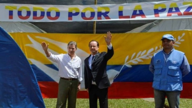 Les présidents colombien, Juan Manuel Santos, et français, François Hollande, sous une bannière "tout pour la paix" lors d'une visite dans un camp de désarmement des Farc, le 24 janvier 2017 à Caldono en Colombie 