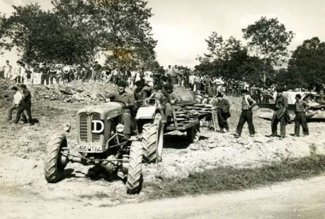 26 juillet 1965. Suite à leur succès au « possessoire » les agriculteurs vont essayer de reprendre effectivement possession de leurs terrains mais ils devront rebrousser chemin sous la menace du bulldozer de l’entreprise DAVID. On est passé là tout près d’un incident grave. On aperçoit au fond les partisans du maire CAMI qui vont conspuer les agriculteurs dans les minutes qui suivront cet instantané. Photo ADPALAA.